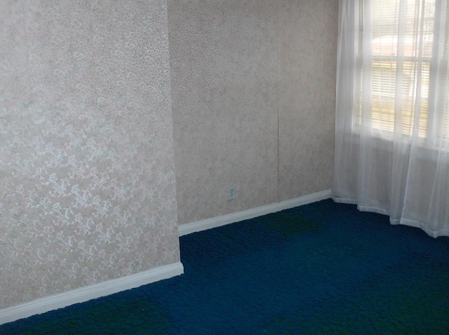 unfurnished room with wallpapered walls, baseboards, and dark colored carpet