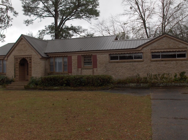 ranch-style house featuring a front yard, brick siding, and metal roof