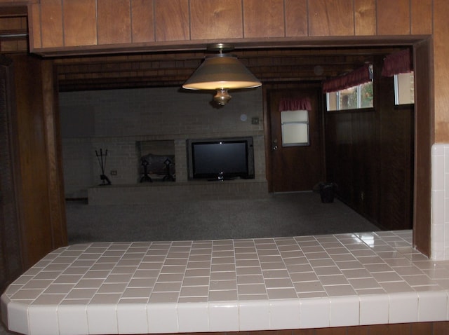 unfurnished living room with wooden walls and a fireplace with raised hearth