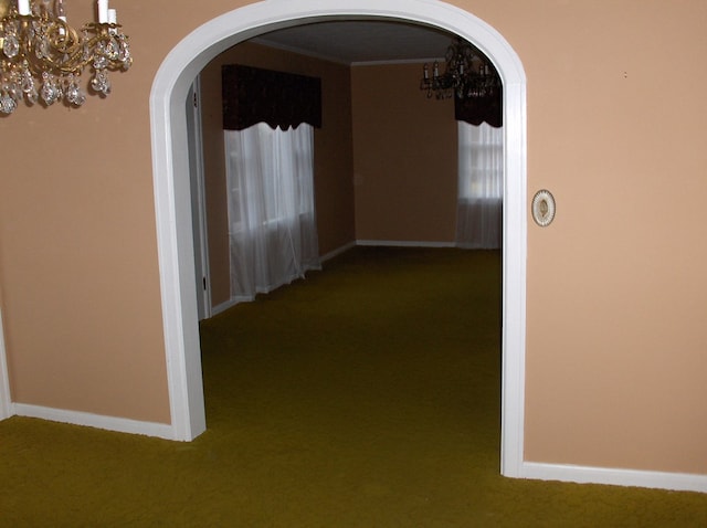 hall featuring baseboards, arched walkways, and carpet