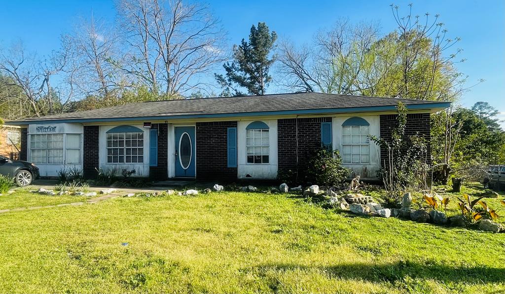 single story home with brick siding, an attached garage, and a front lawn