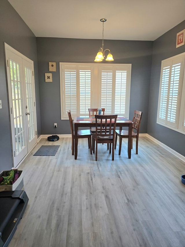 dining room featuring french doors, a chandelier, and light wood-type flooring