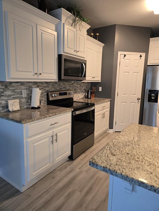 kitchen featuring white cabinetry, backsplash, appliances with stainless steel finishes, and light hardwood / wood-style flooring