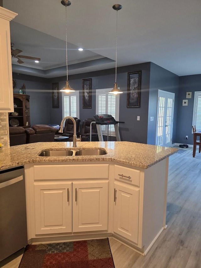 kitchen with white cabinets, light hardwood / wood-style flooring, stainless steel dishwasher, and sink