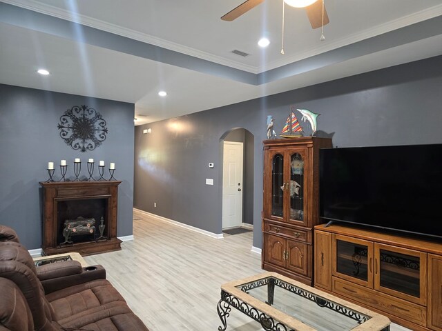 living room with light hardwood / wood-style flooring, ceiling fan, and crown molding