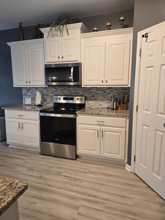 kitchen with white cabinets, stainless steel appliances, and light hardwood / wood-style flooring