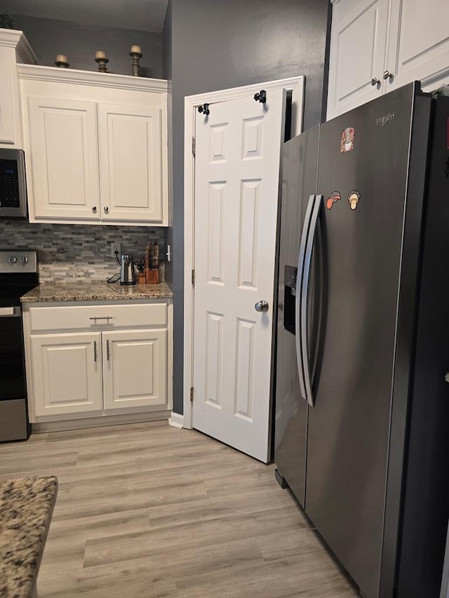 kitchen with white cabinets, light stone countertops, light wood-type flooring, and appliances with stainless steel finishes