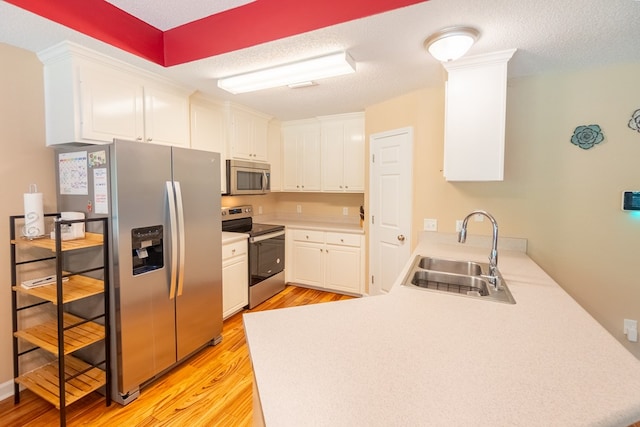 330 Brushfire Dr, Dothan, AL 36305 - kitchen with appliances with stainless steel finishes, a peninsula, light wood-type flooring, white cabinets, and a textured ceiling