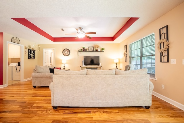 330 Brushfire Dr, Dothan, AL 36305 - living room with a ceiling fan, a tray ceiling, light wood-type flooring, and washer and dryer