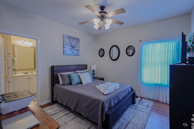 bedroom featuring ceiling fan, ensuite bath, and light hardwood / wood-style flooring