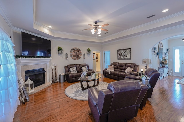 living room with hardwood / wood-style flooring, ornamental molding, a fireplace, and a tray ceiling