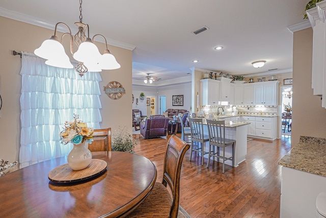 dining area with ornamental molding, sink, hardwood / wood-style floors, and ceiling fan