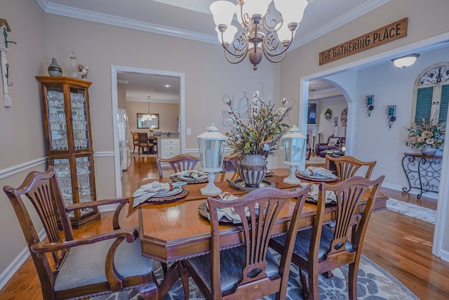 dining area with hardwood / wood-style flooring, ornamental molding, and a notable chandelier