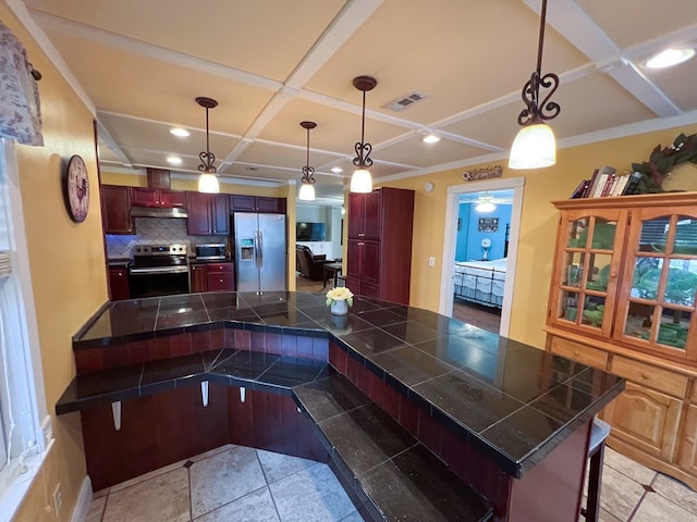 kitchen featuring visible vents, under cabinet range hood, a kitchen bar, coffered ceiling, and stainless steel appliances