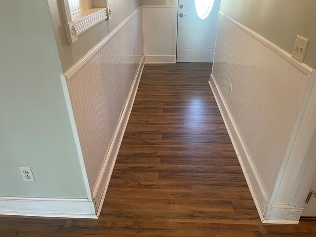 corridor featuring wood finished floors and a wainscoted wall