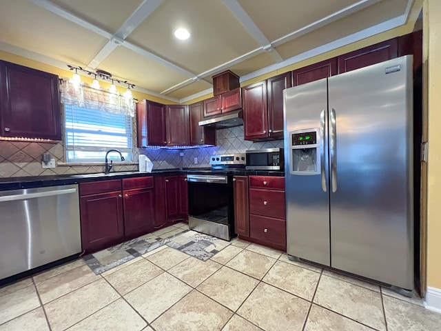 kitchen with dark brown cabinets, appliances with stainless steel finishes, under cabinet range hood, dark countertops, and tasteful backsplash