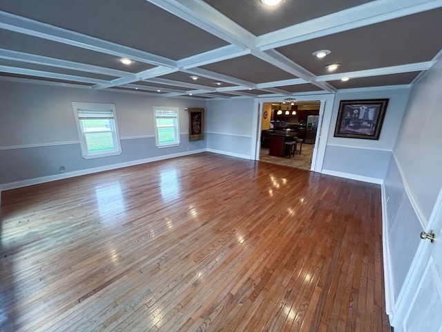 unfurnished living room featuring beamed ceiling, baseboards, coffered ceiling, and hardwood / wood-style floors