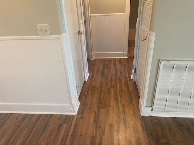 hallway featuring a wainscoted wall, visible vents, and wood finished floors