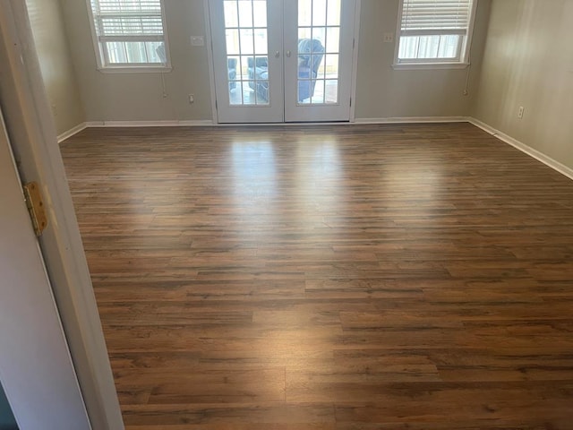 unfurnished room with dark wood-style floors, plenty of natural light, and baseboards