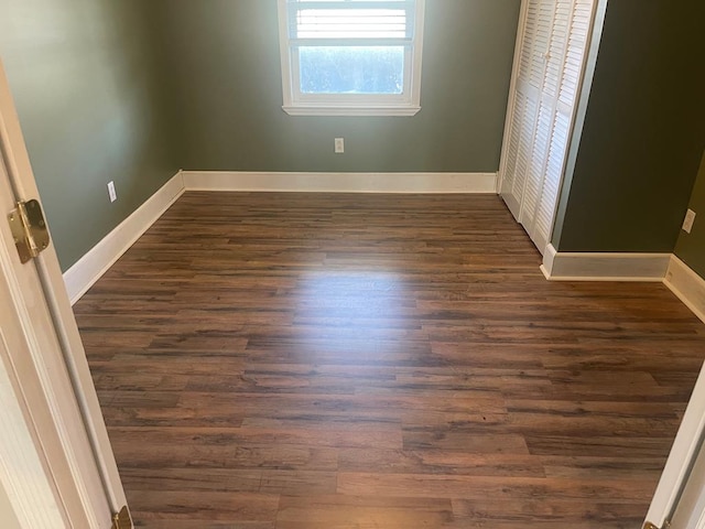 empty room featuring dark wood-type flooring and baseboards