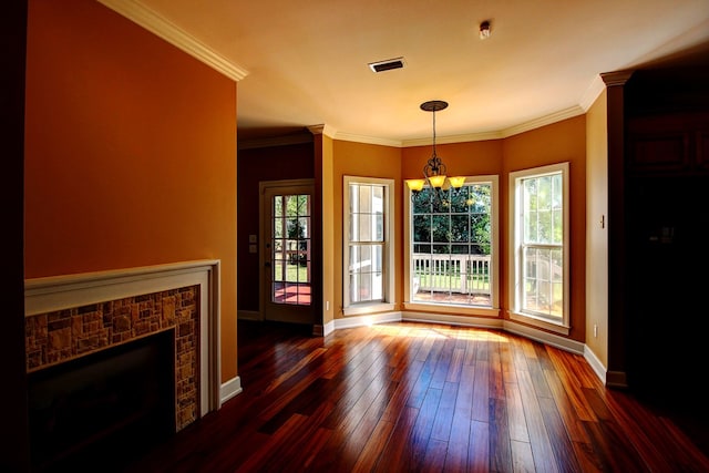 unfurnished dining area featuring a brick fireplace, crown molding, dark hardwood / wood-style flooring, and a notable chandelier