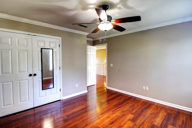 unfurnished bedroom featuring a closet, dark hardwood / wood-style floors, ceiling fan, and crown molding