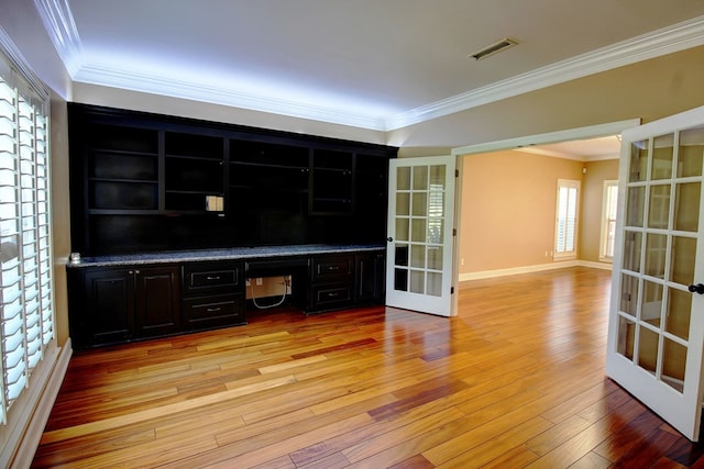 interior space with french doors, built in desk, crown molding, and light hardwood / wood-style flooring