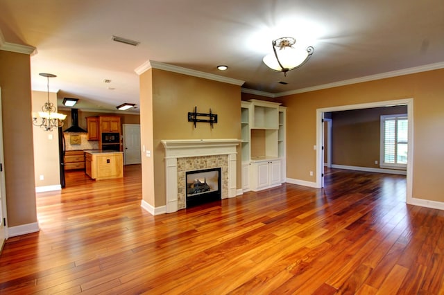 unfurnished living room with a notable chandelier, crown molding, and light hardwood / wood-style flooring