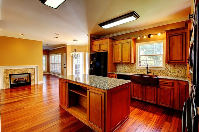 kitchen with sink, black fridge, backsplash, wood-type flooring, and a kitchen island