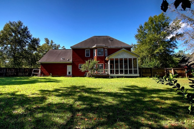 rear view of property featuring a sunroom and a yard