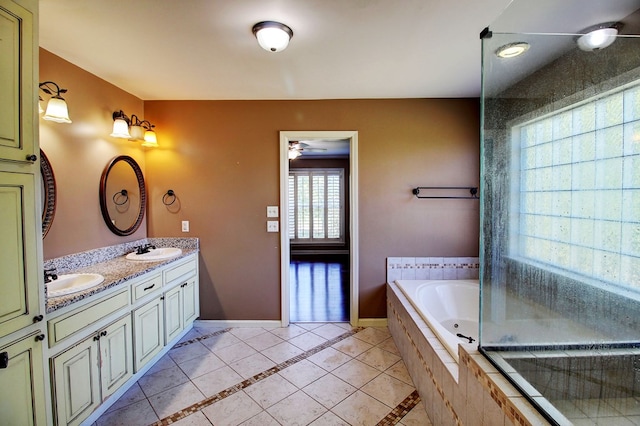 bathroom with tile patterned flooring, ceiling fan, vanity, and tiled tub