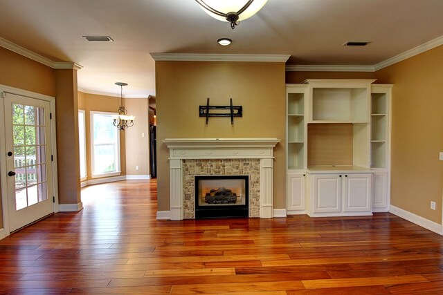 unfurnished living room featuring a tile fireplace, hardwood / wood-style floors, a chandelier, and ornamental molding