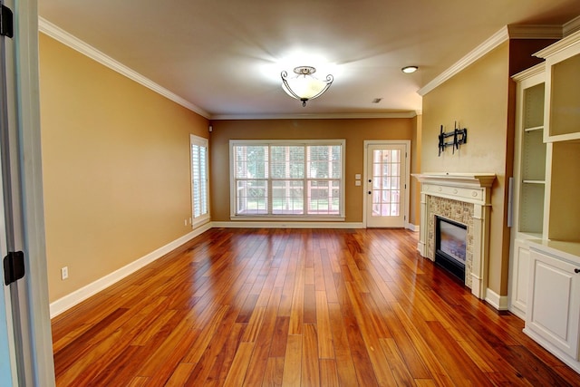 unfurnished living room featuring hardwood / wood-style floors, a stone fireplace, and crown molding