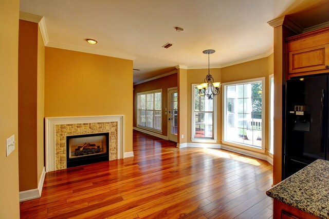 kitchen with a fireplace, hardwood / wood-style flooring, black fridge, and plenty of natural light