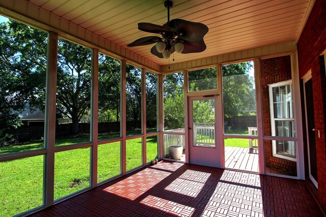 unfurnished sunroom with ceiling fan, wood ceiling, and a wealth of natural light