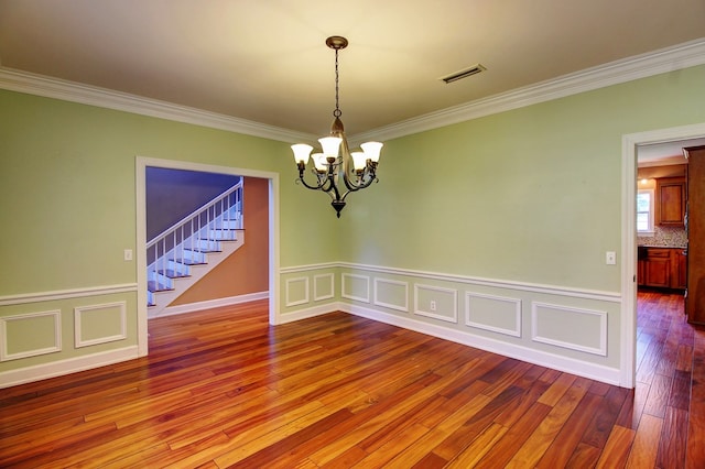 unfurnished room with wood-type flooring, ornamental molding, and an inviting chandelier