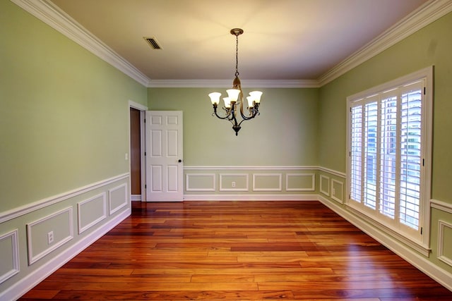 empty room with hardwood / wood-style floors, crown molding, and an inviting chandelier