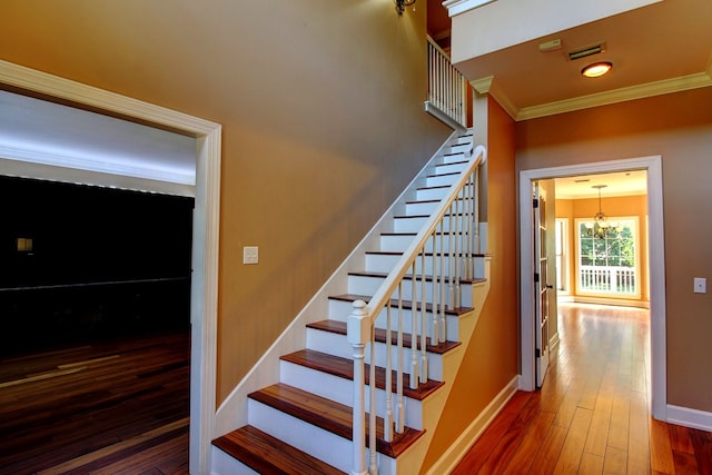 staircase featuring hardwood / wood-style flooring, a notable chandelier, and ornamental molding