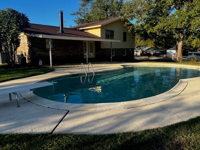 view of swimming pool with a diving board and a patio area