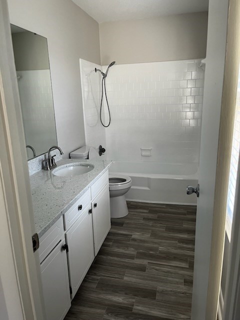 full bathroom featuring wood-type flooring, vanity, toilet, and tiled shower / bath combo