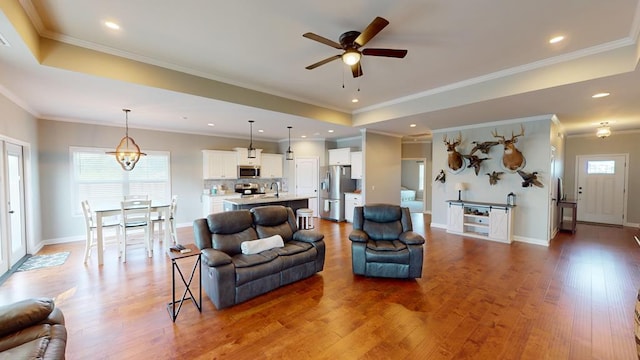 living room with crown molding, hardwood / wood-style floors, and ceiling fan with notable chandelier