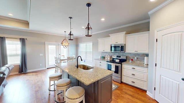 kitchen featuring sink, light stone countertops, appliances with stainless steel finishes, plenty of natural light, and white cabinetry