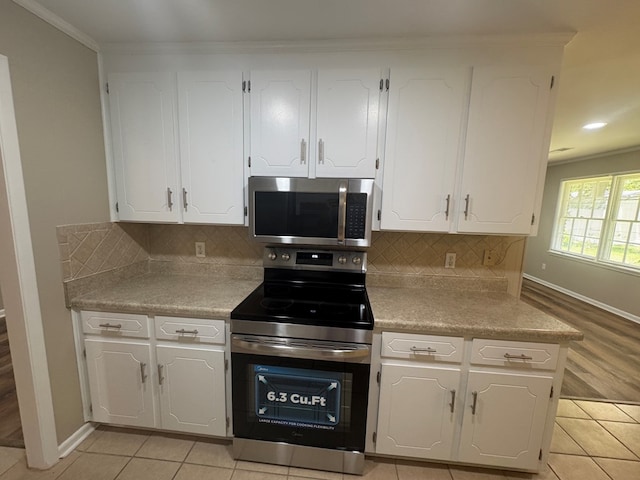 411 Kentworth Dr, Dothan, AL 36301 - kitchen with appliances with stainless steel finishes, white cabinets, backsplash, light countertops, and ornamental molding