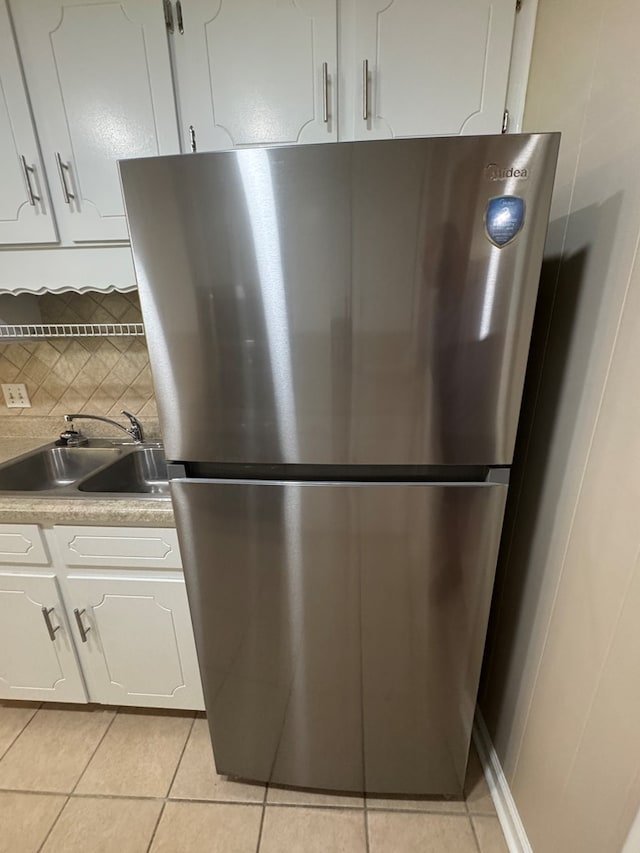 411 Kentworth Dr, Dothan, AL 36301 - kitchen with freestanding refrigerator, light tile patterned flooring, white cabinetry, and backsplash