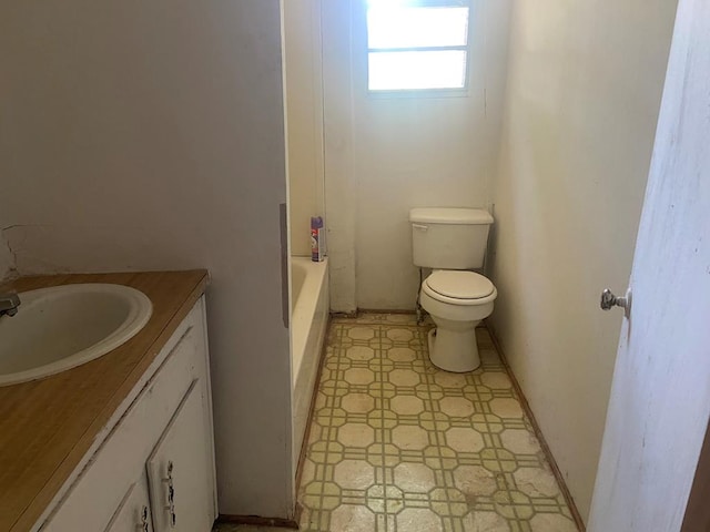 bathroom with vanity, a tub to relax in, and toilet