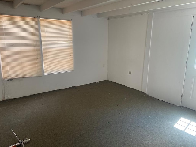 unfurnished room with plenty of natural light and beam ceiling