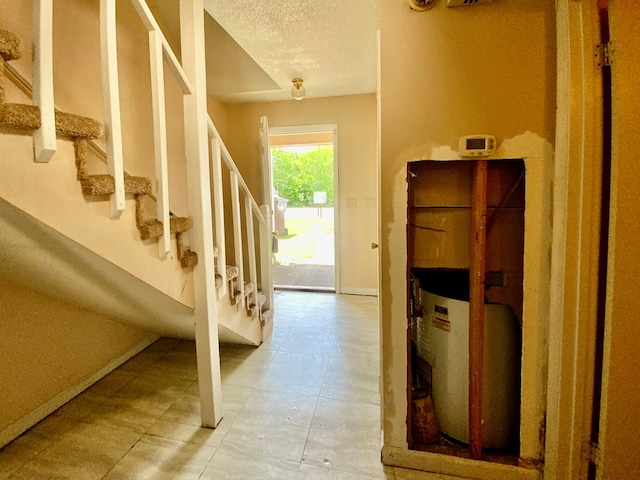 interior space featuring baseboards, tile patterned floors, stairs, and a textured ceiling