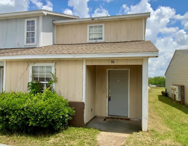 entrance to property with a lawn and roof with shingles