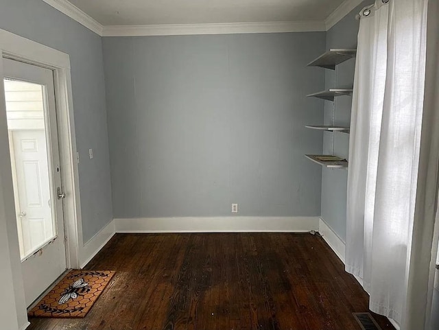 spare room featuring baseboards, ornamental molding, and wood finished floors