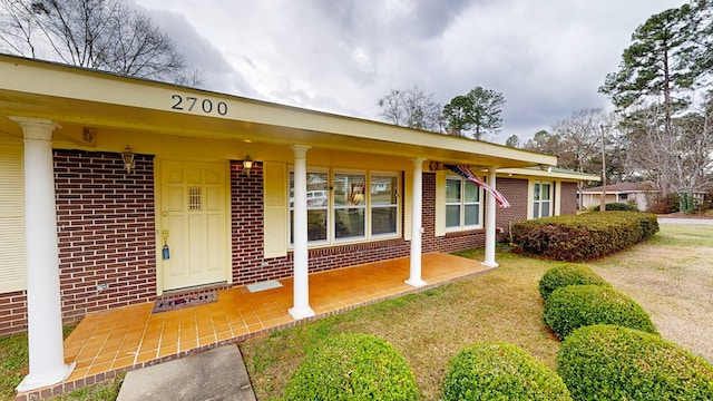 view of exterior entry featuring a porch and brick siding